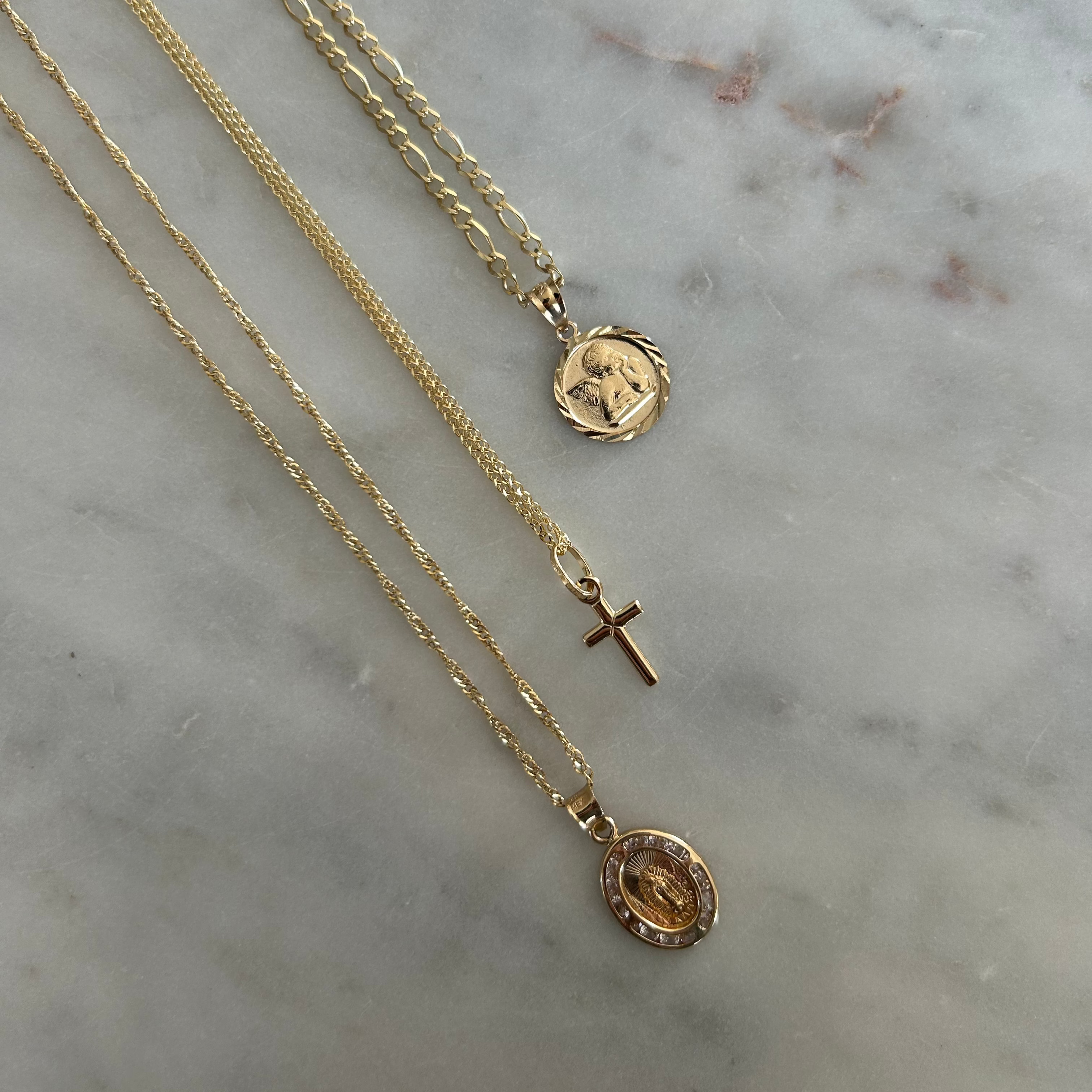 image of three gold necklaces with three different pendant charms on a marble backdrop