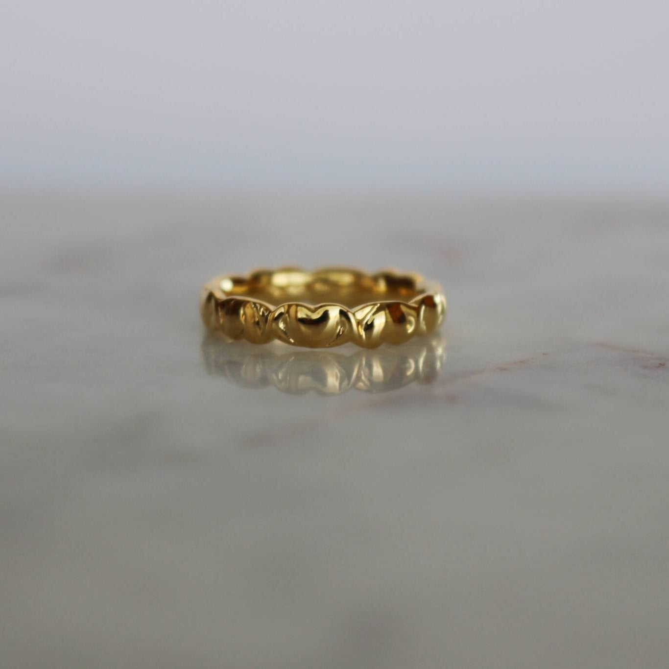 image of a gold heart ring on top of a marble table
