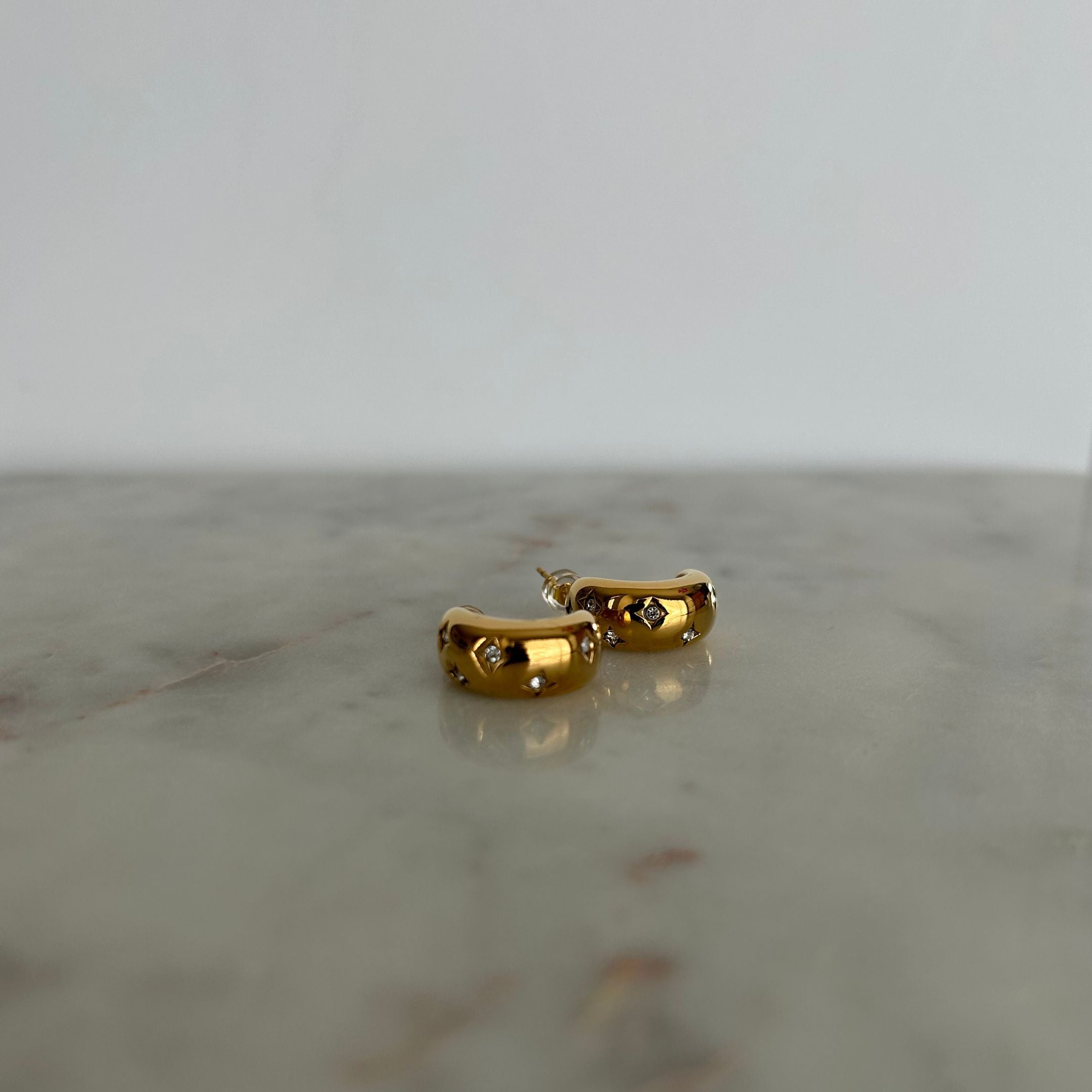 image of gold earrings on a marble table