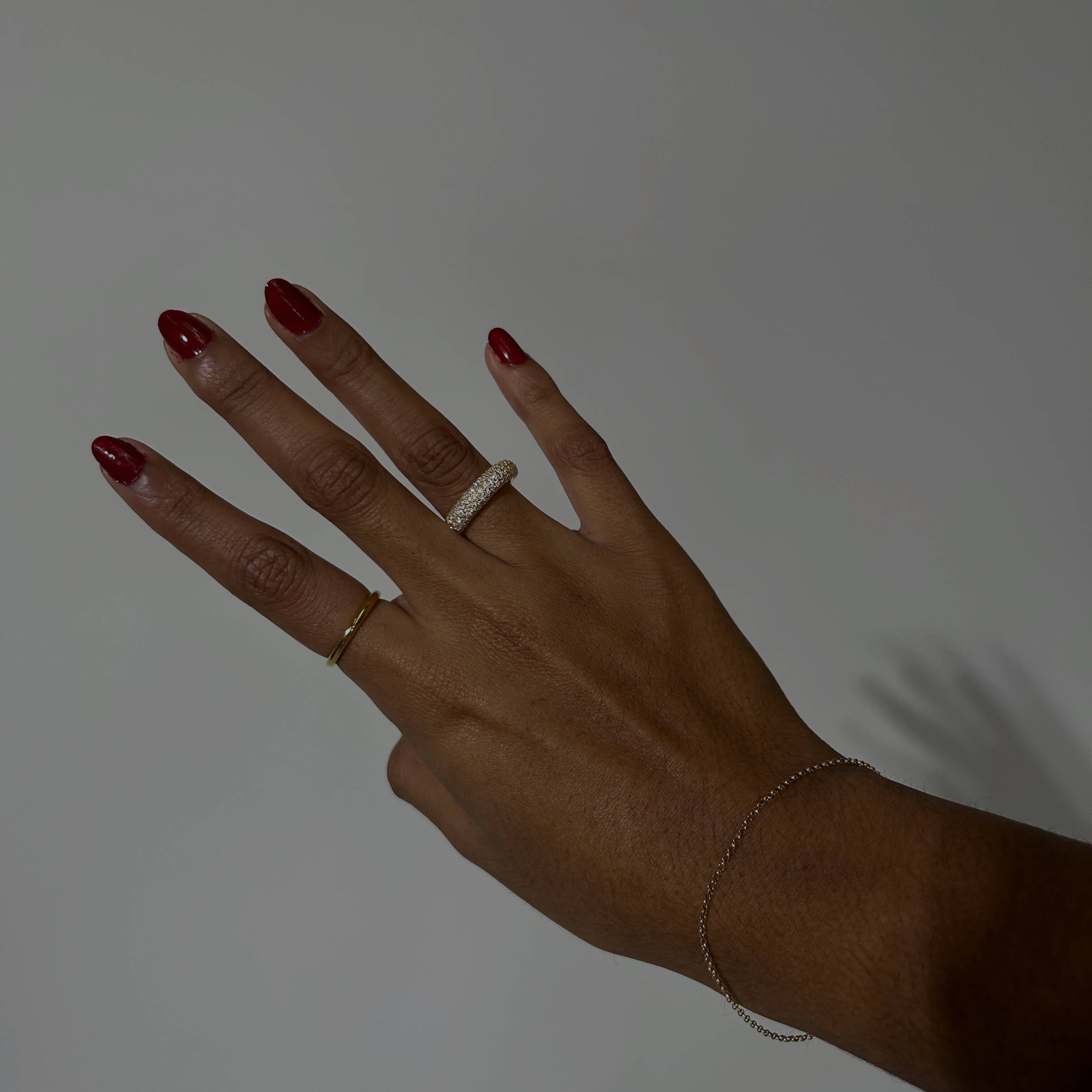 image of a woman's hand against a white backdrop with two gold rings on