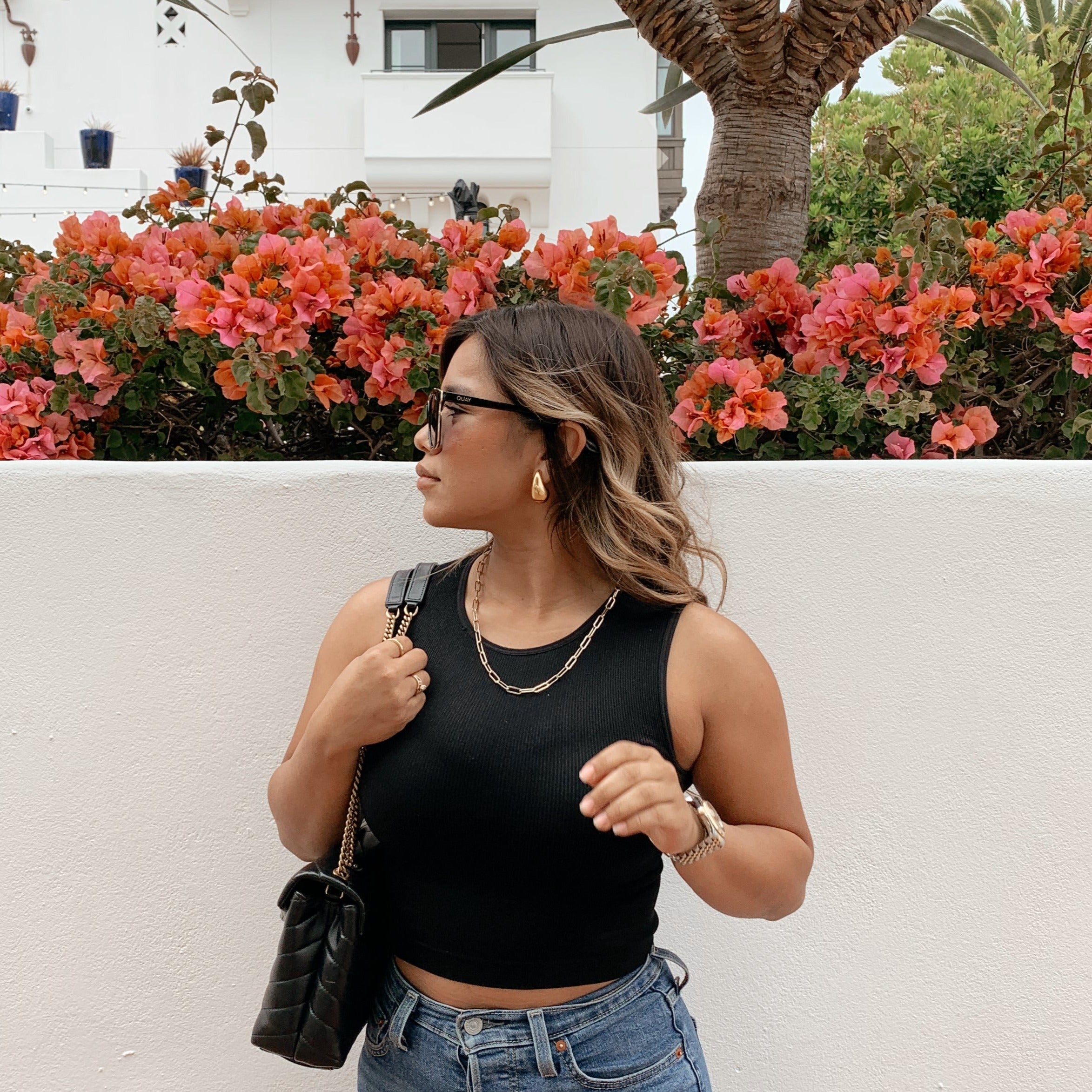 woman looking to the side wearing gold teardrop earrings and a paperclip bracelet
