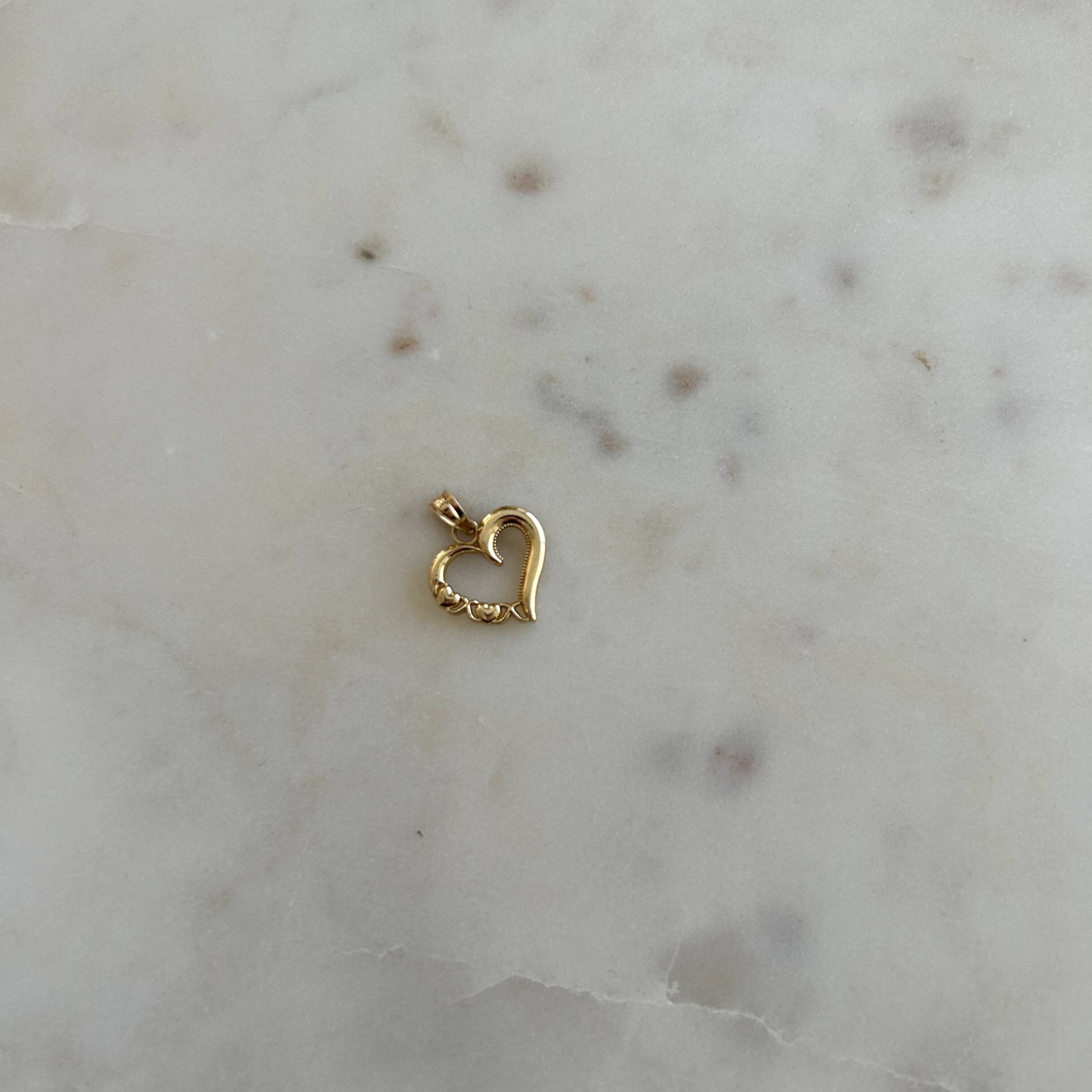 image of a gold heart pendant on top of a marble backdrop