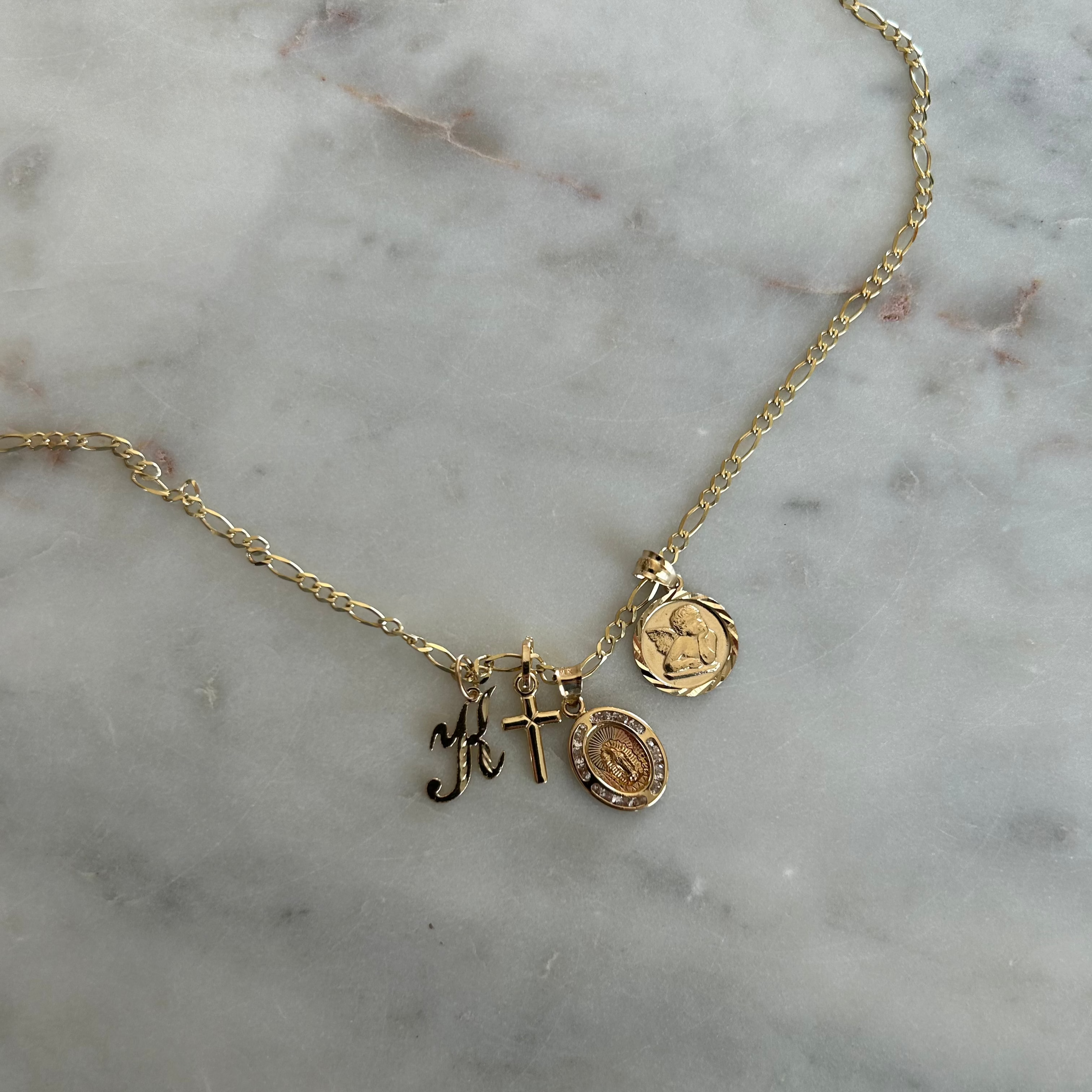 charm pendants on a necklace against a marble backdrop