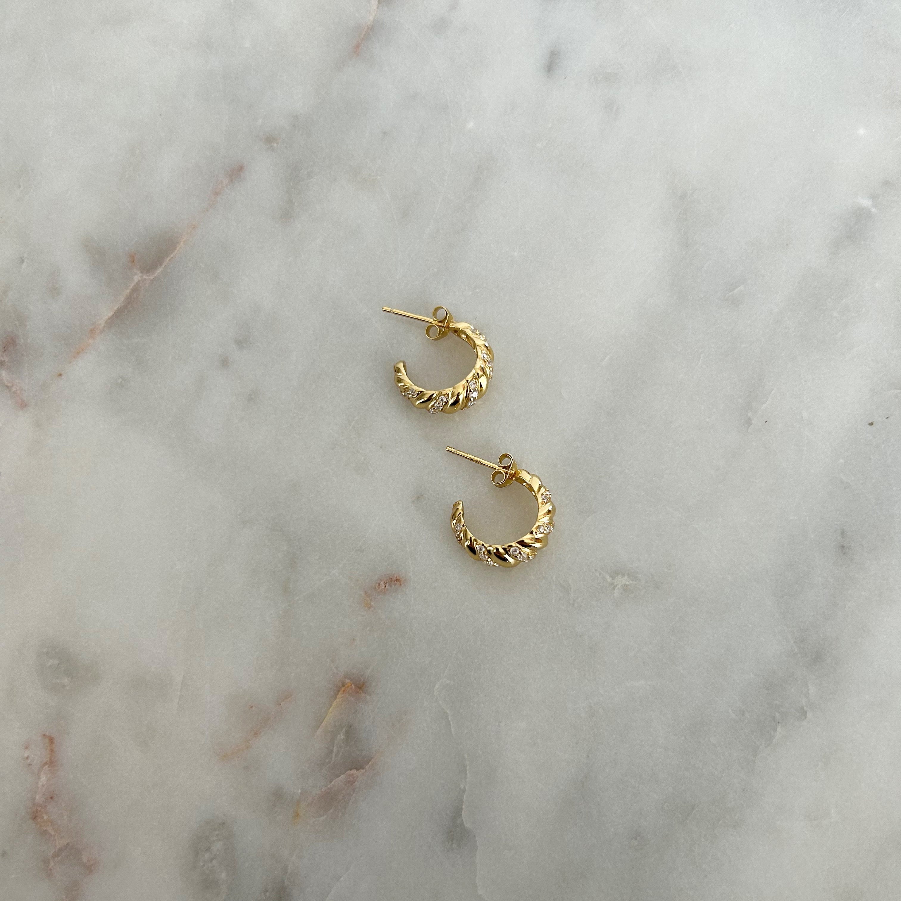 image of gold earrings on a marble table