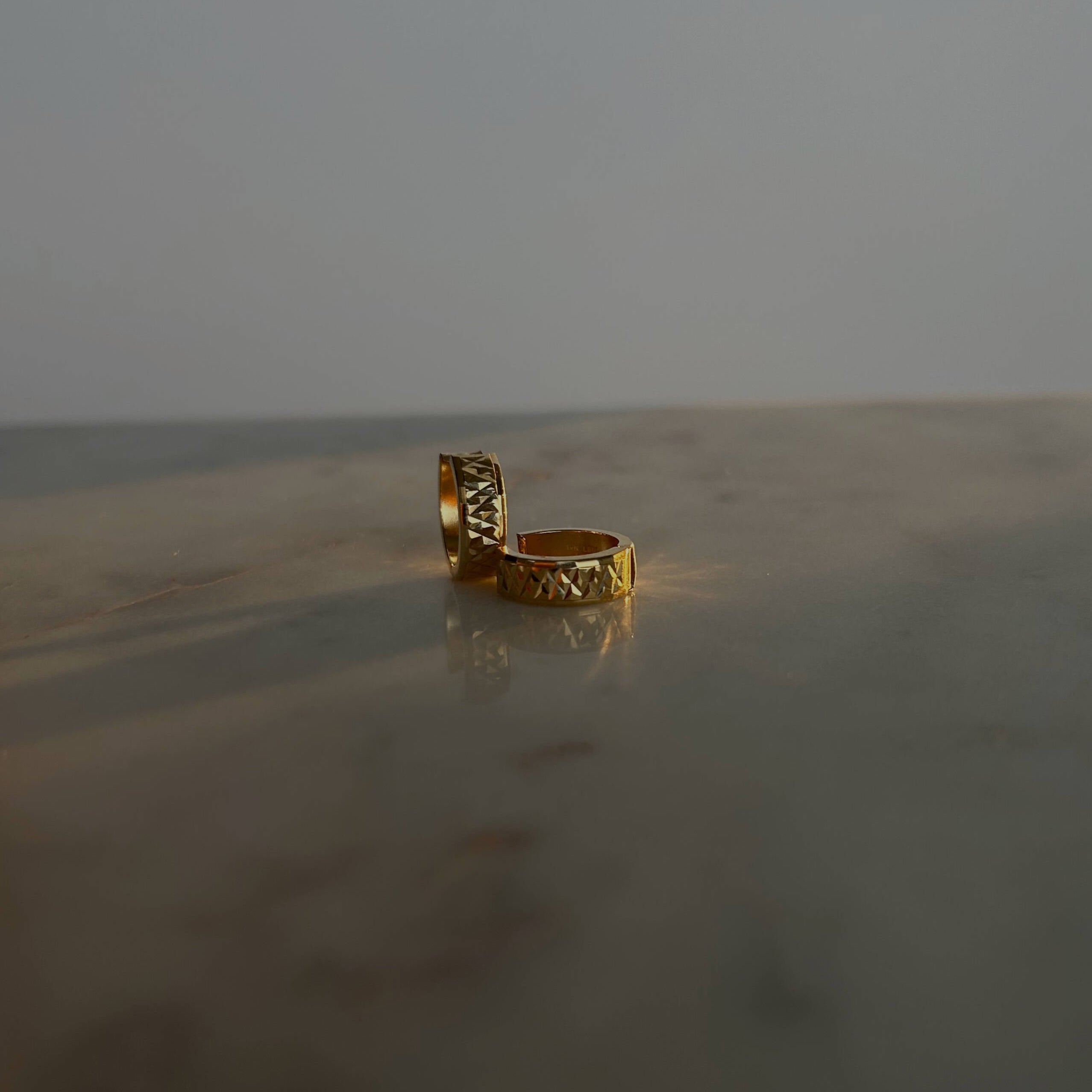 image of gold hoop earrings on a marble table against a white backdrop