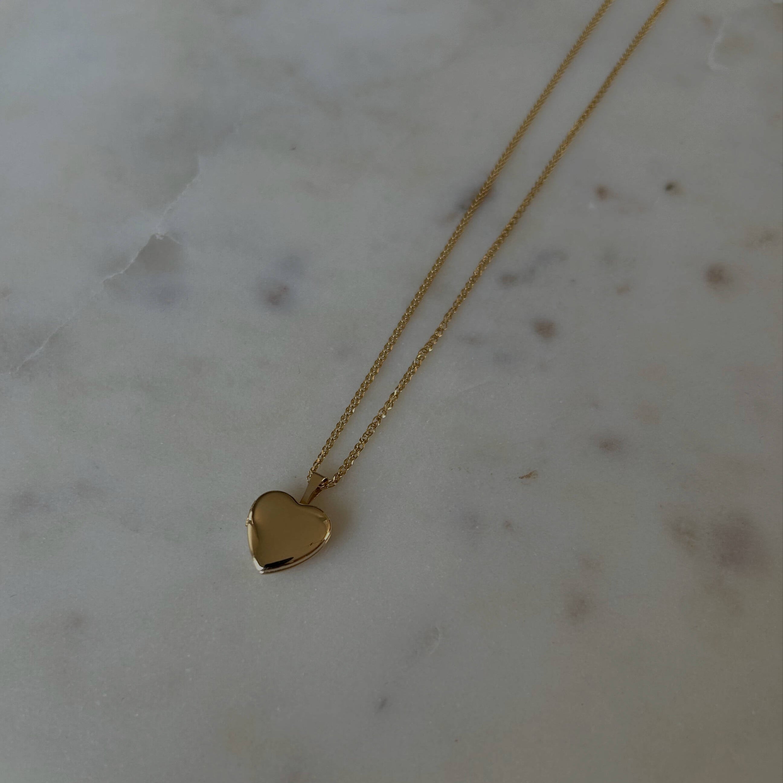 photo of a gold heat locket necklace on top of a marble table