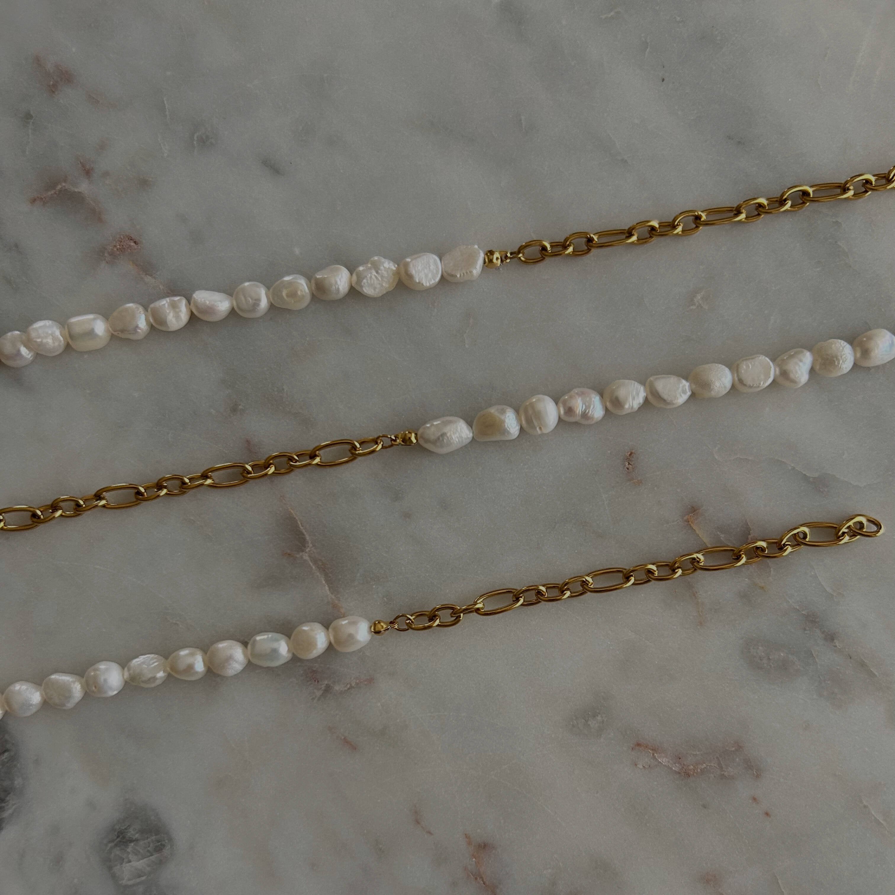 image of three pearl chain bracelets on a marble table