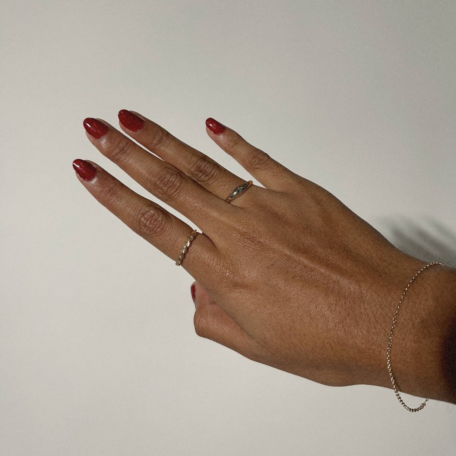 image of a womans hands with two gold rings against a white backdrop
