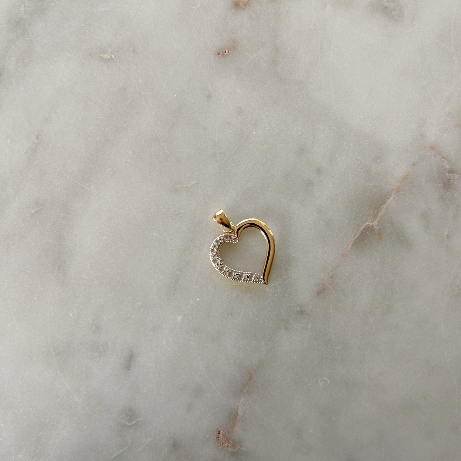 image of a two tone heart pendant on a marble table
