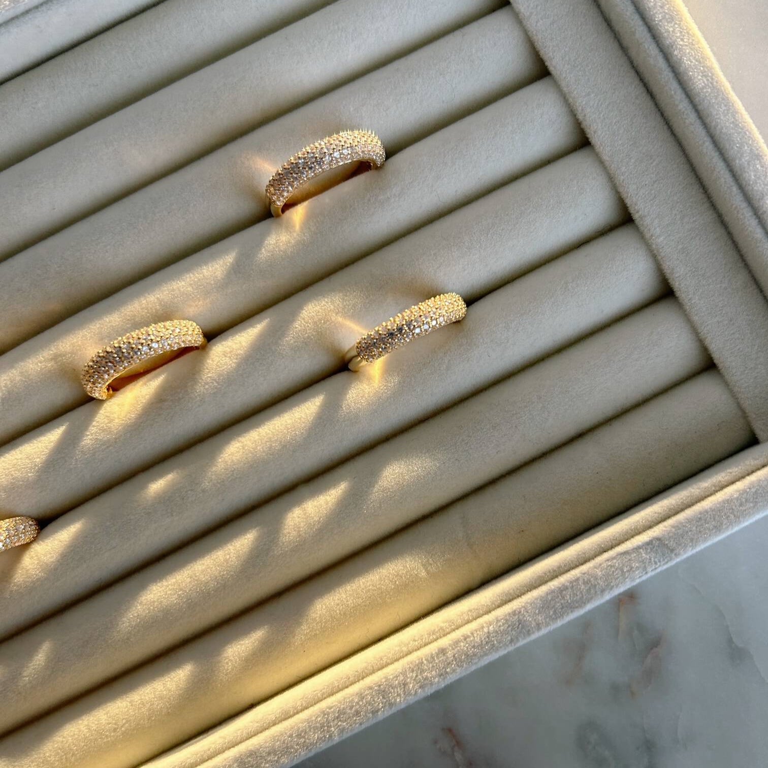 image of four pave gold rings on a ring tray holder on top of a marble floor