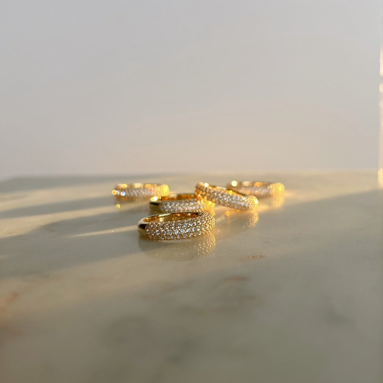 image of five gold pave ring on a marble table stacked on top of each other