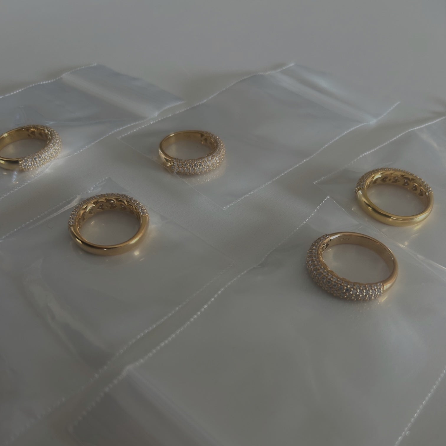 image of five gold pave rings in a jewelry bag on top of a white table
