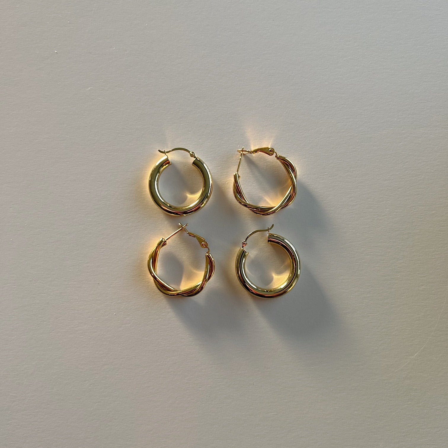 image of four gold hoop earrings on top of a white backdrop