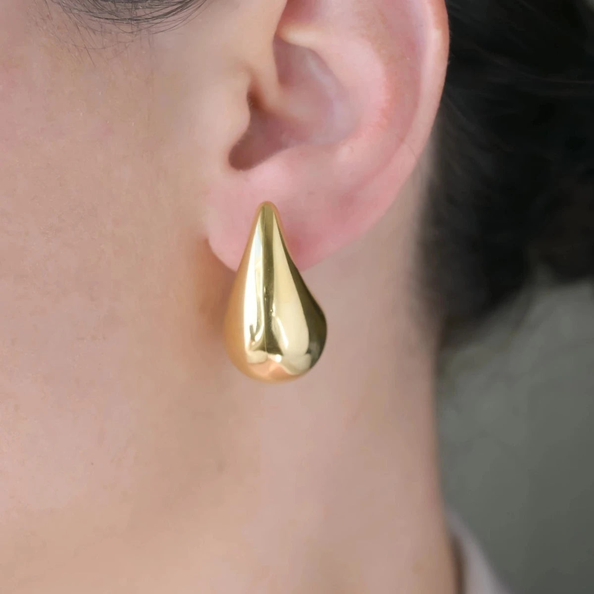 woman with large gold teardrop earrings