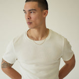 Person wearing a white shirt against a plain background