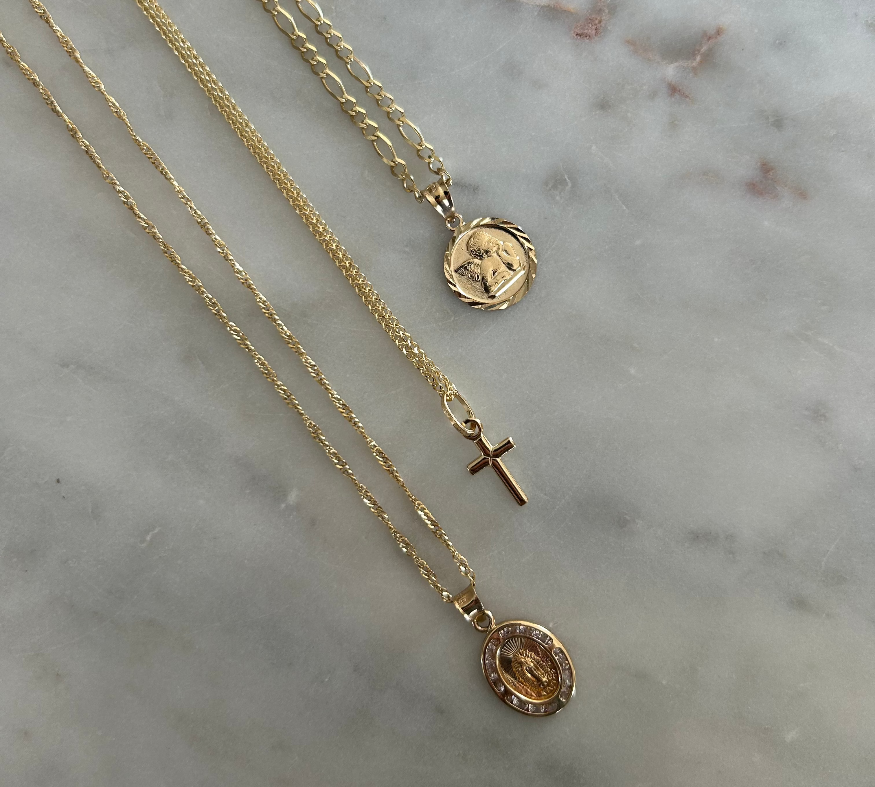 image of three gold necklaces with three different pendant charms on a marble backdrop