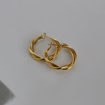 image of two twisted gold hoops on top of each other against a white backdrop