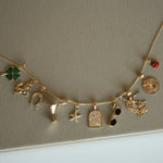 Gold necklace with various charms on a beige background