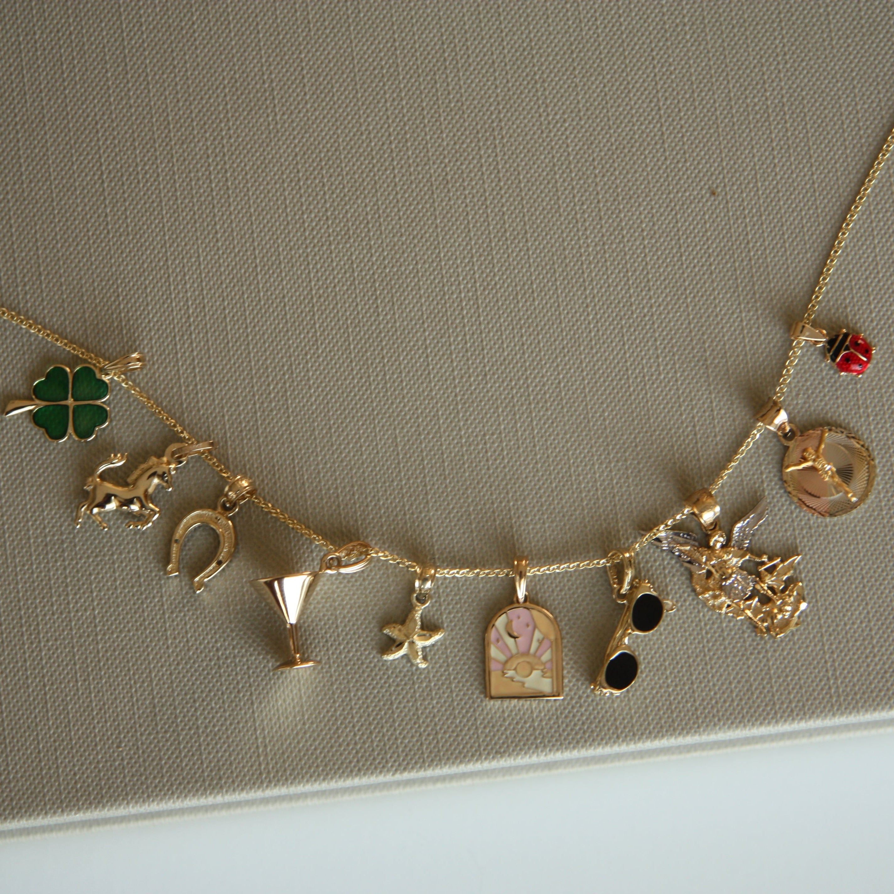 Gold necklace with various charms on a beige background