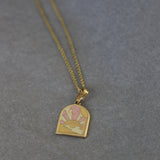 Gold necklace with a heart-shaped pendant on a gray background