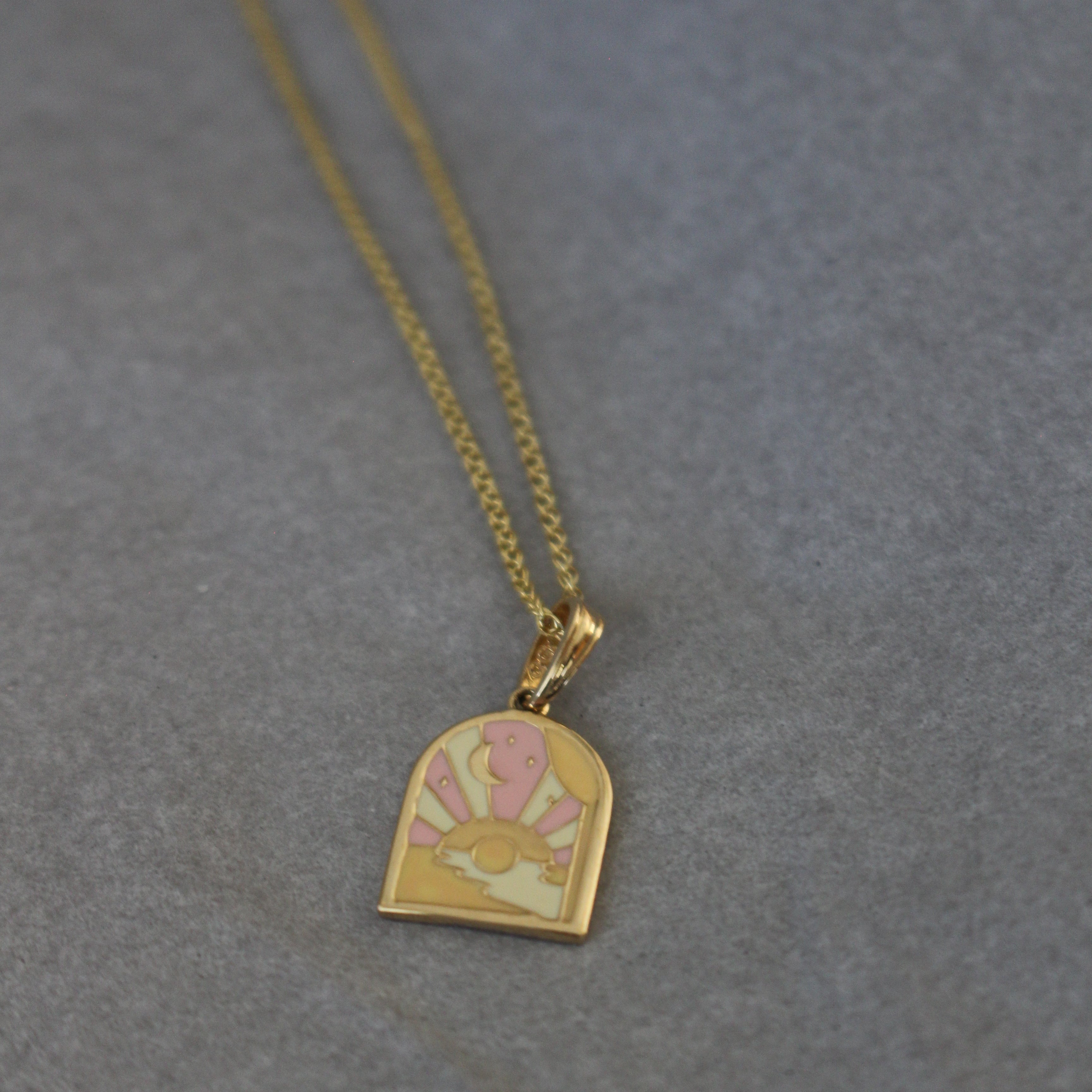 Gold necklace with a heart-shaped pendant on a gray background