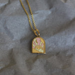 Gold necklace with a decorative pendant on crumpled gray paper