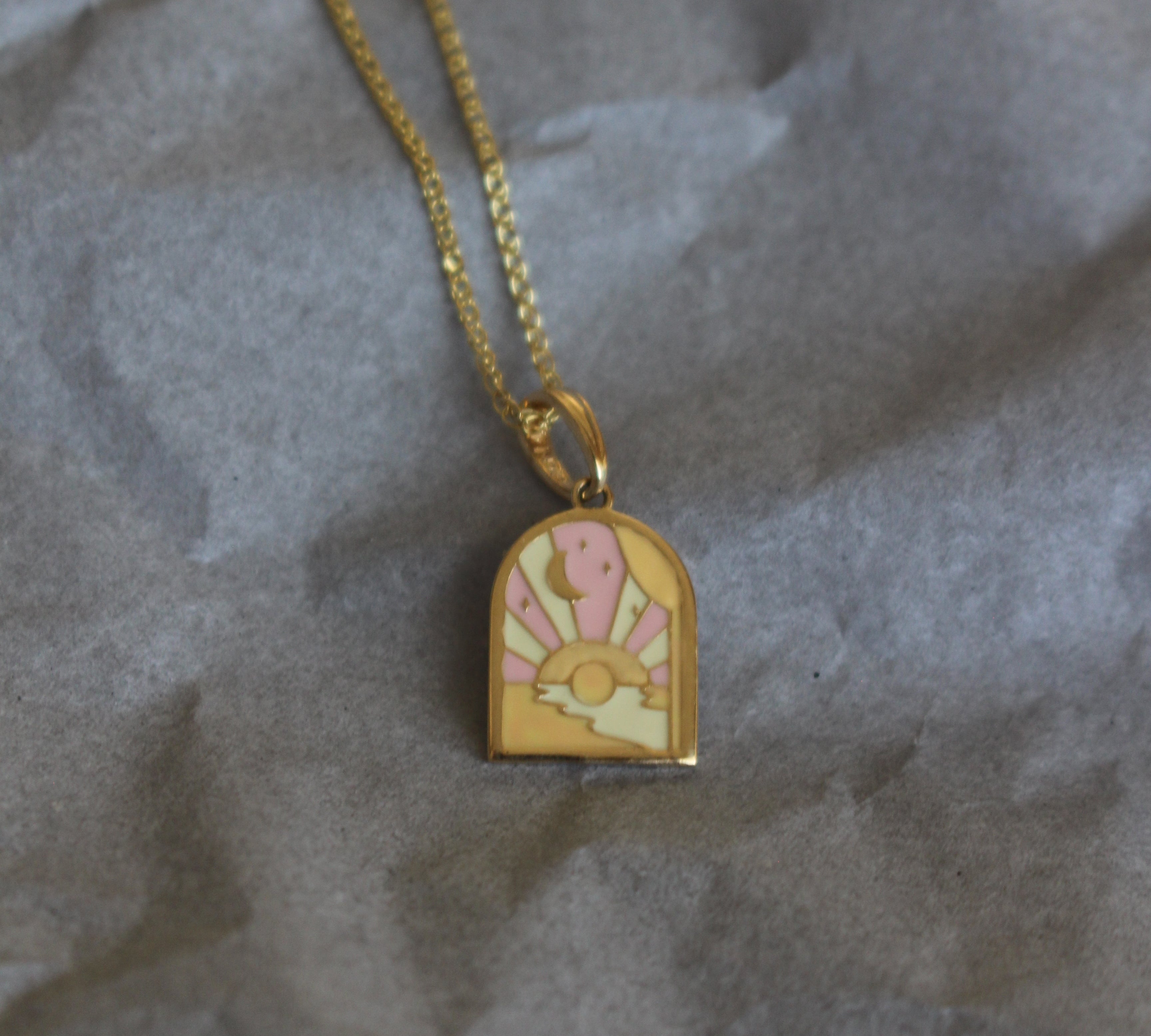 Gold necklace with a decorative pendant on crumpled gray paper