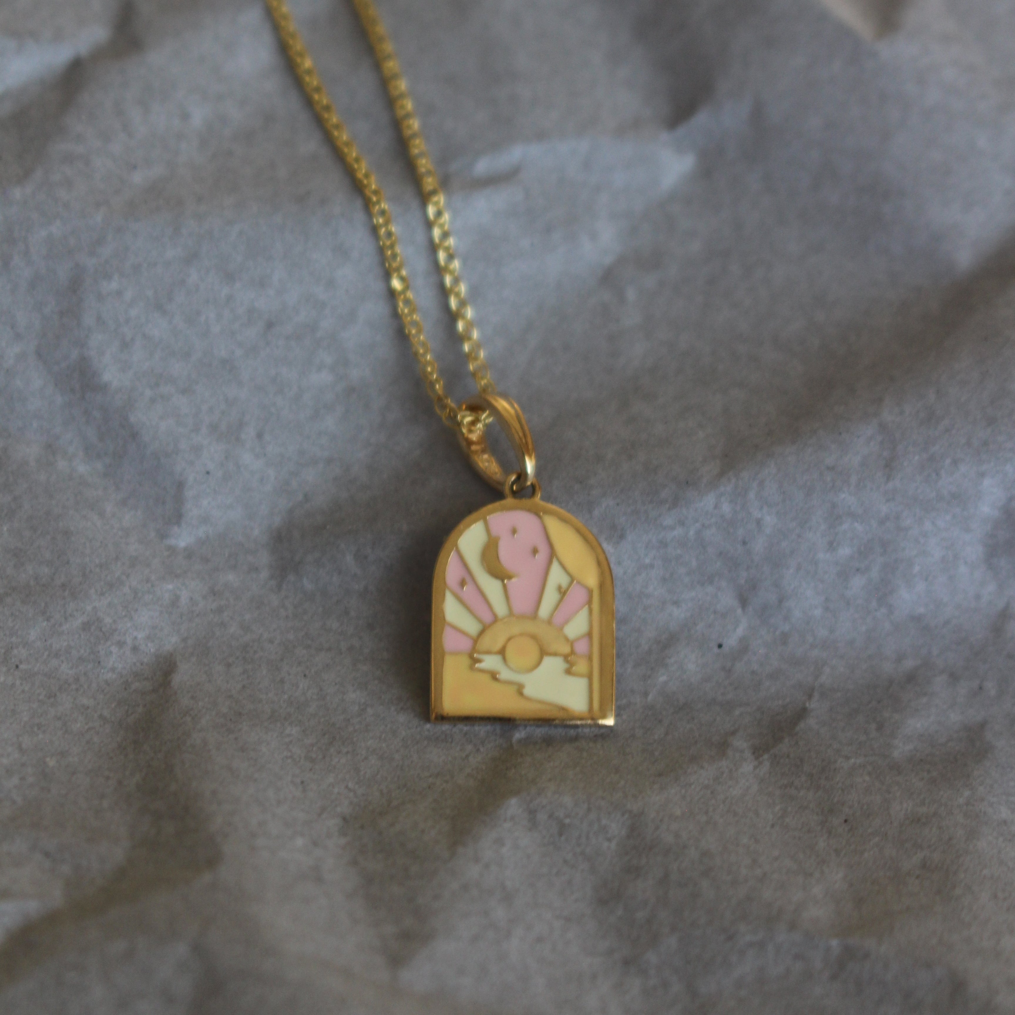 Gold necklace with a decorative pendant on crumpled gray paper