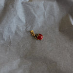 Small gold earring with a red gemstone on crumpled paper