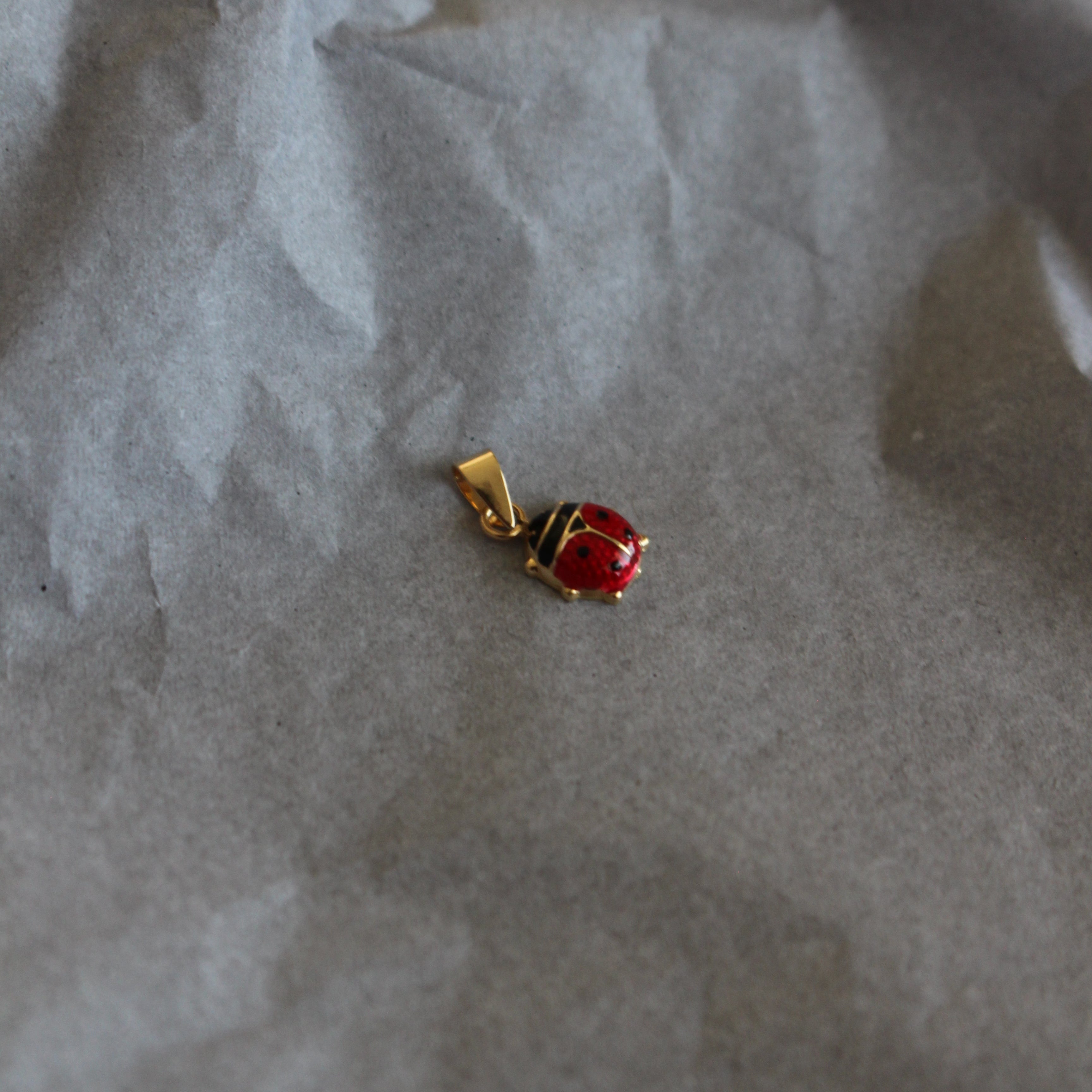 Small gold earring with a red gemstone on crumpled paper