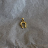 Gold horseshoe charm on crumpled brown paper