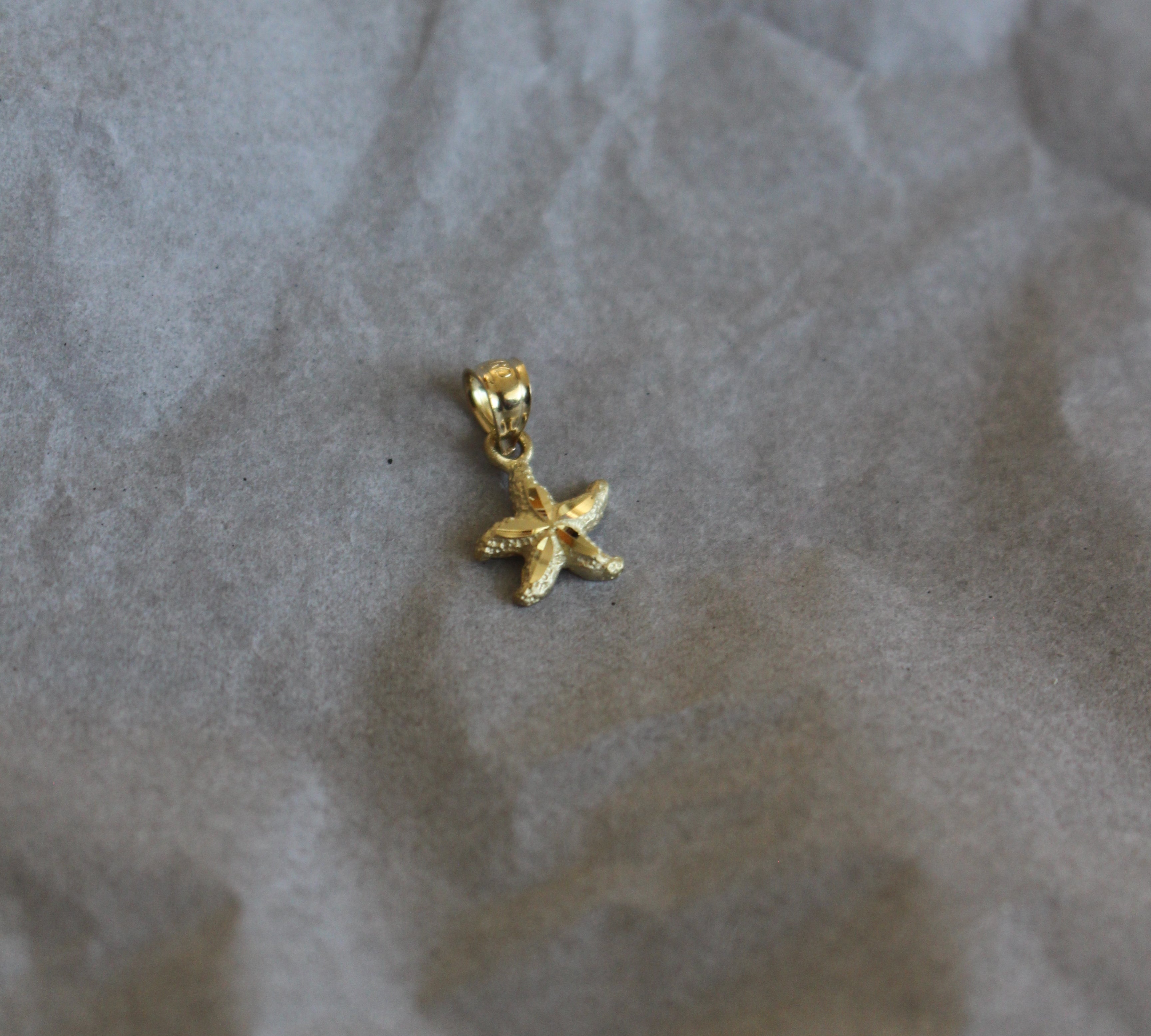Gold star-shaped earring on crumpled paper