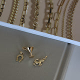 Gold jewelry including necklaces and earrings displayed on a neutral background