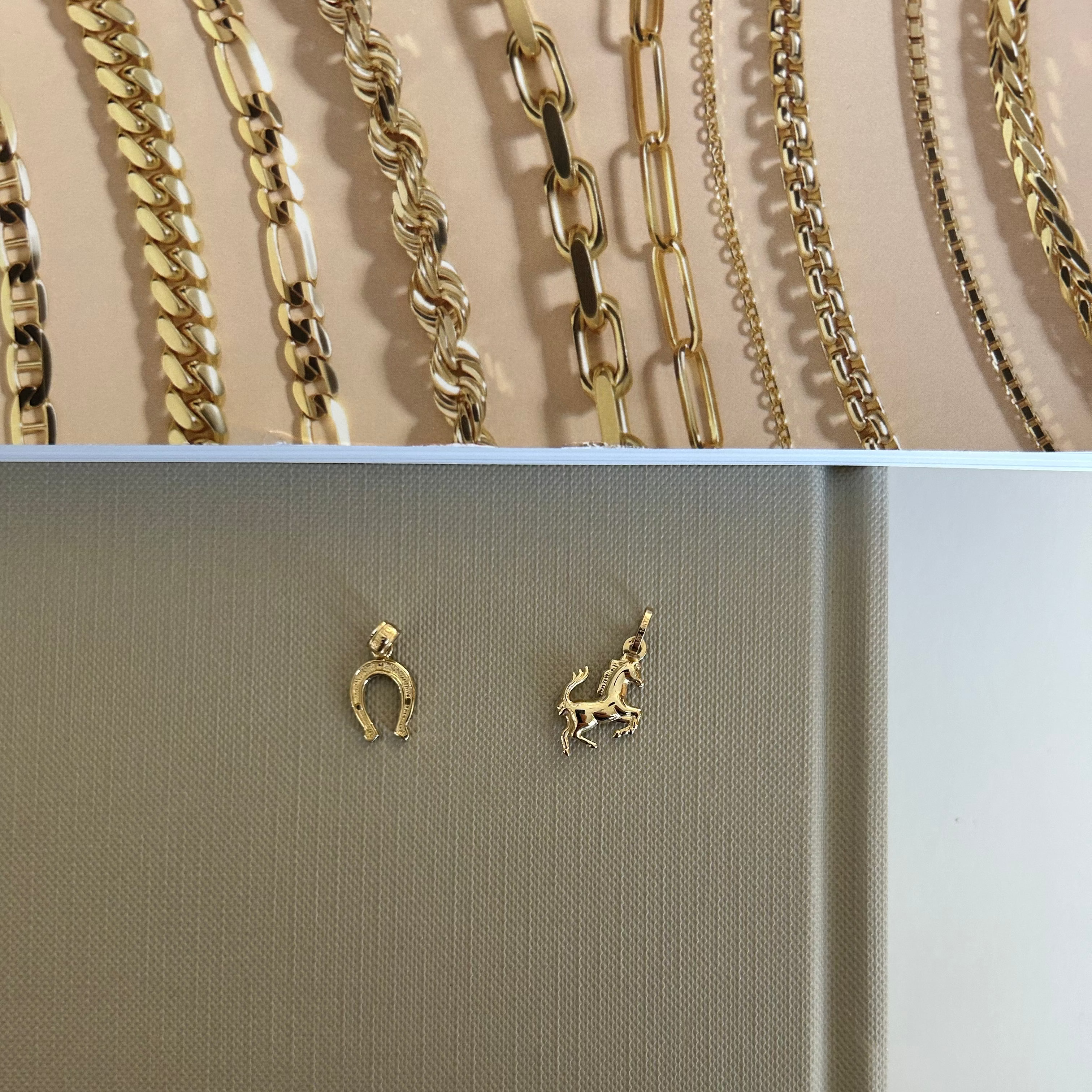 Top: Assorted gold chains on a beige background. Bottom: Two gold charms on a beige card.