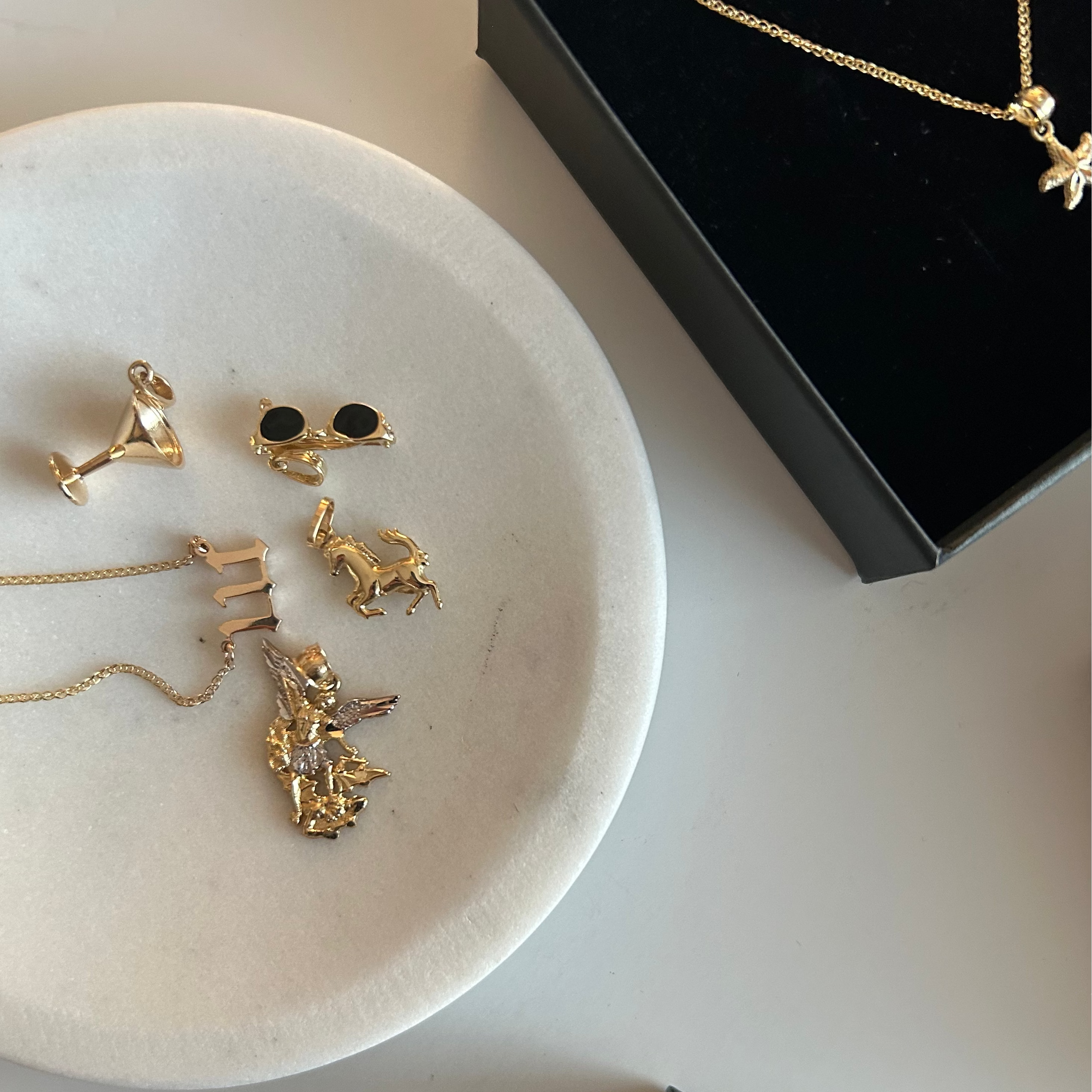 Gold necklaces on a white dish with a black box in the background
