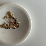 Gold necklaces with charms on a white plate