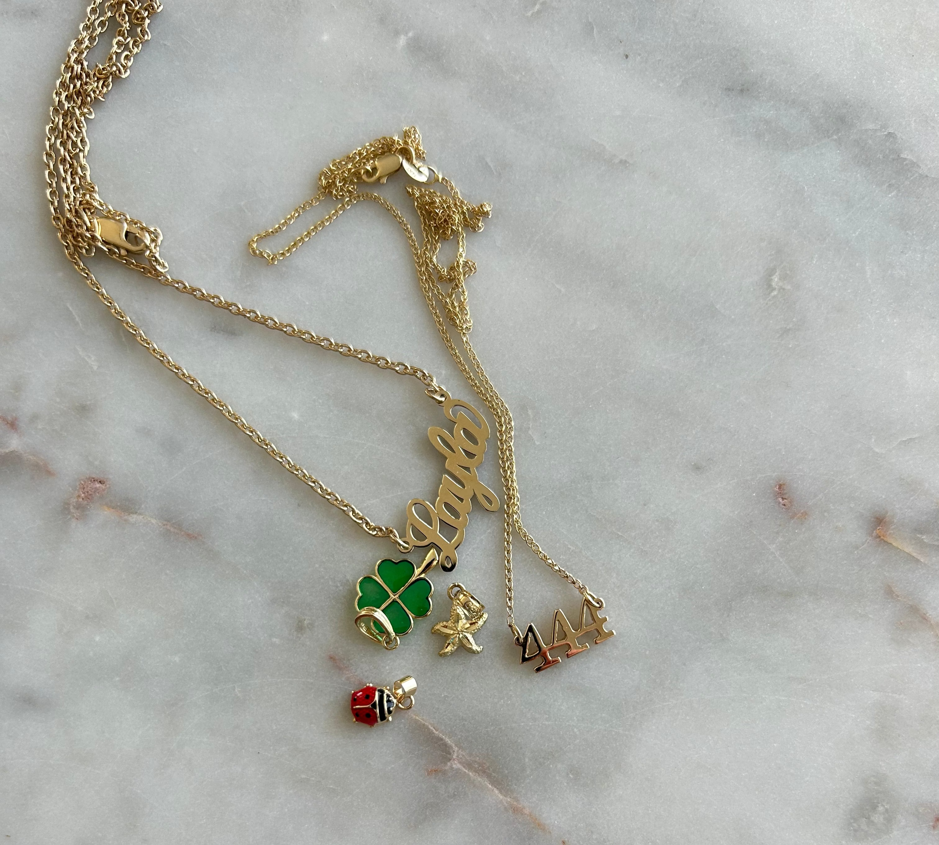 Gold necklace with charms on a marble surface