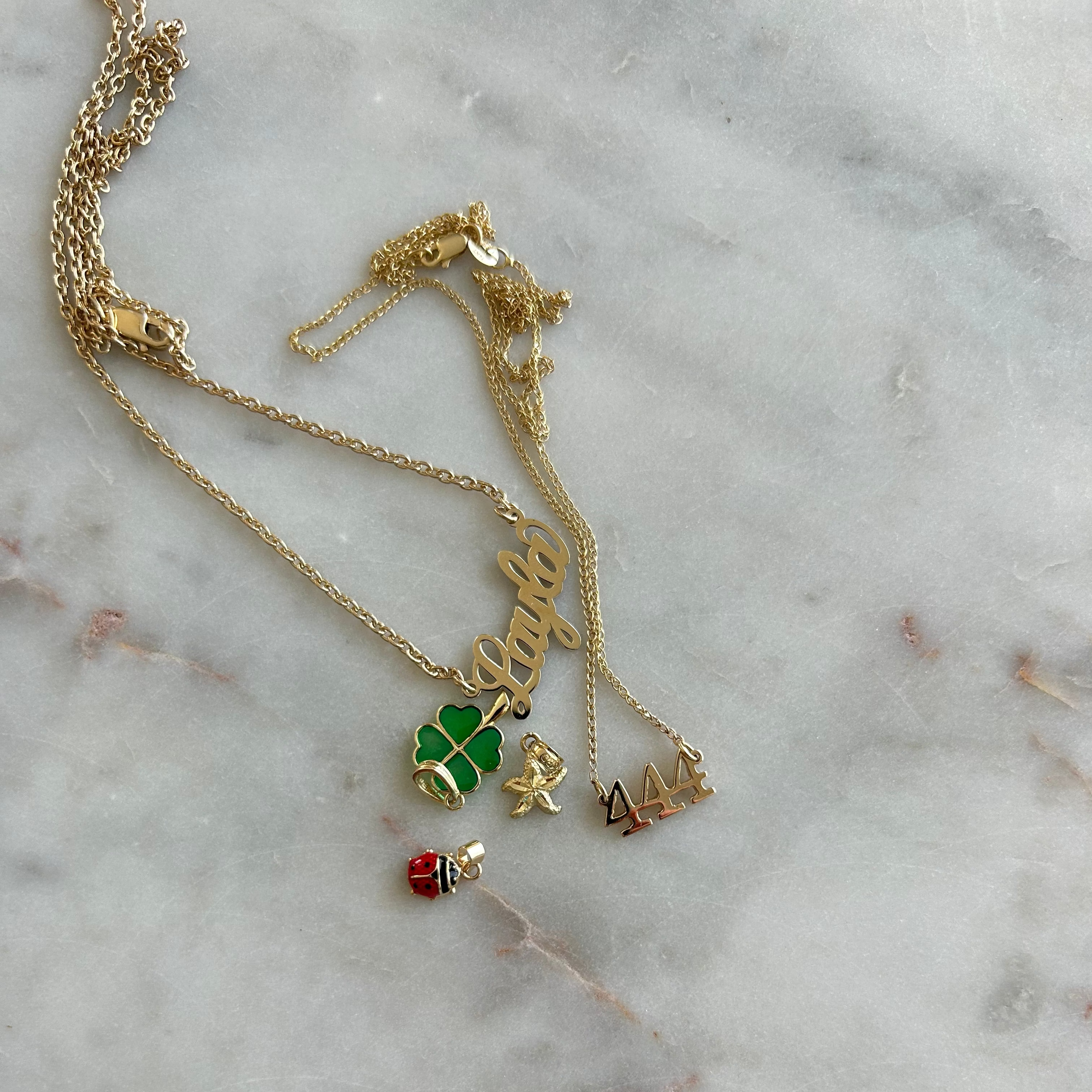 Gold necklace with charms on a marble surface