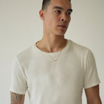 Man wearing a plain white t-shirt against a neutral background