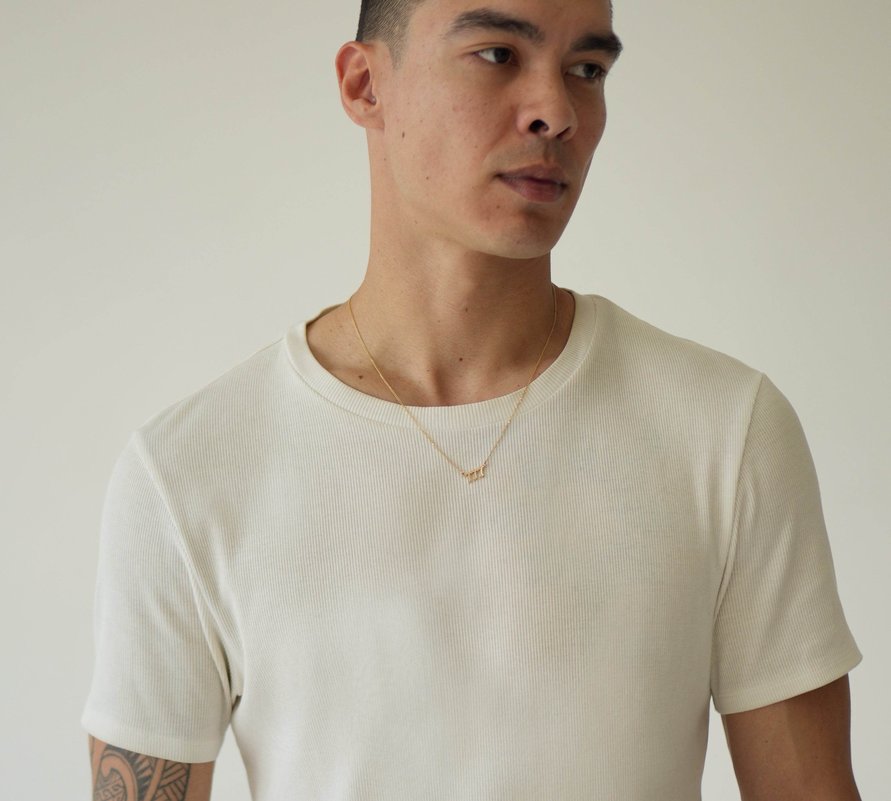 Man wearing a plain white t-shirt against a neutral background