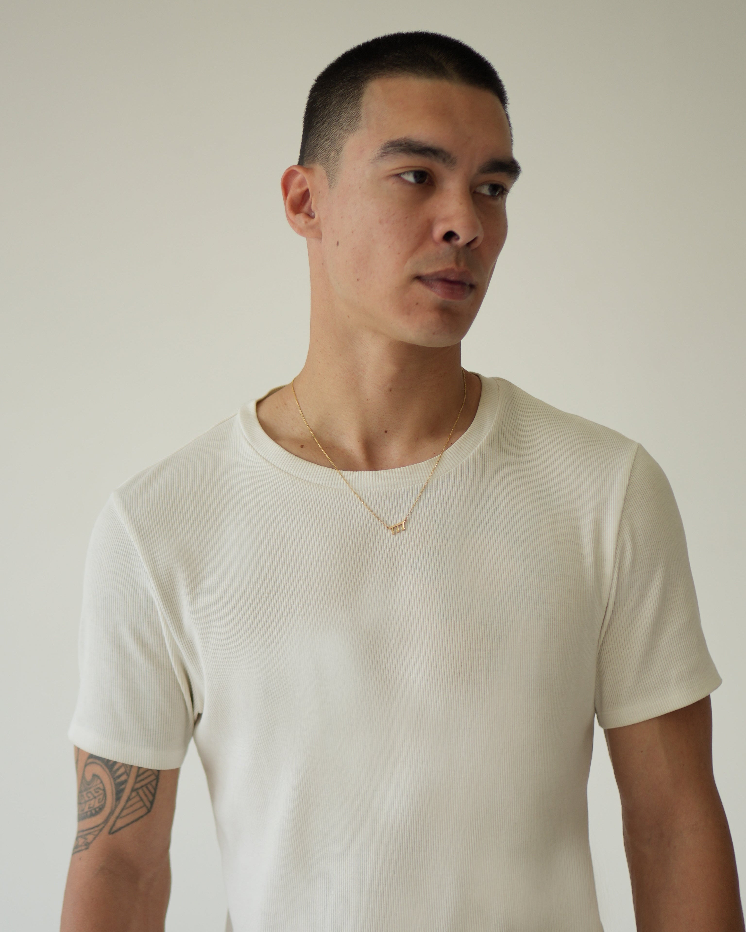 Man wearing a plain white t-shirt against a neutral background