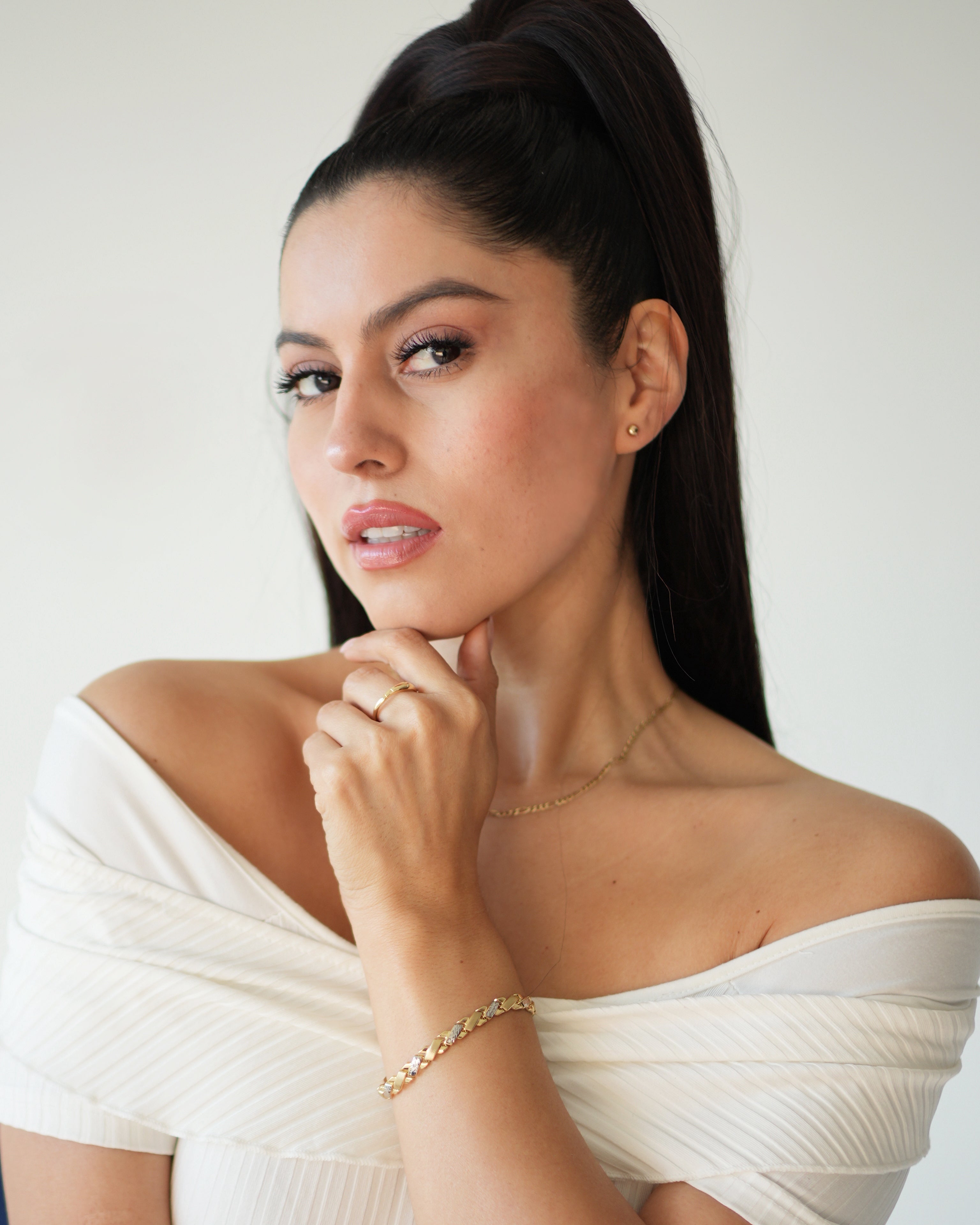Woman wearing a white off-shoulder top with a plain background