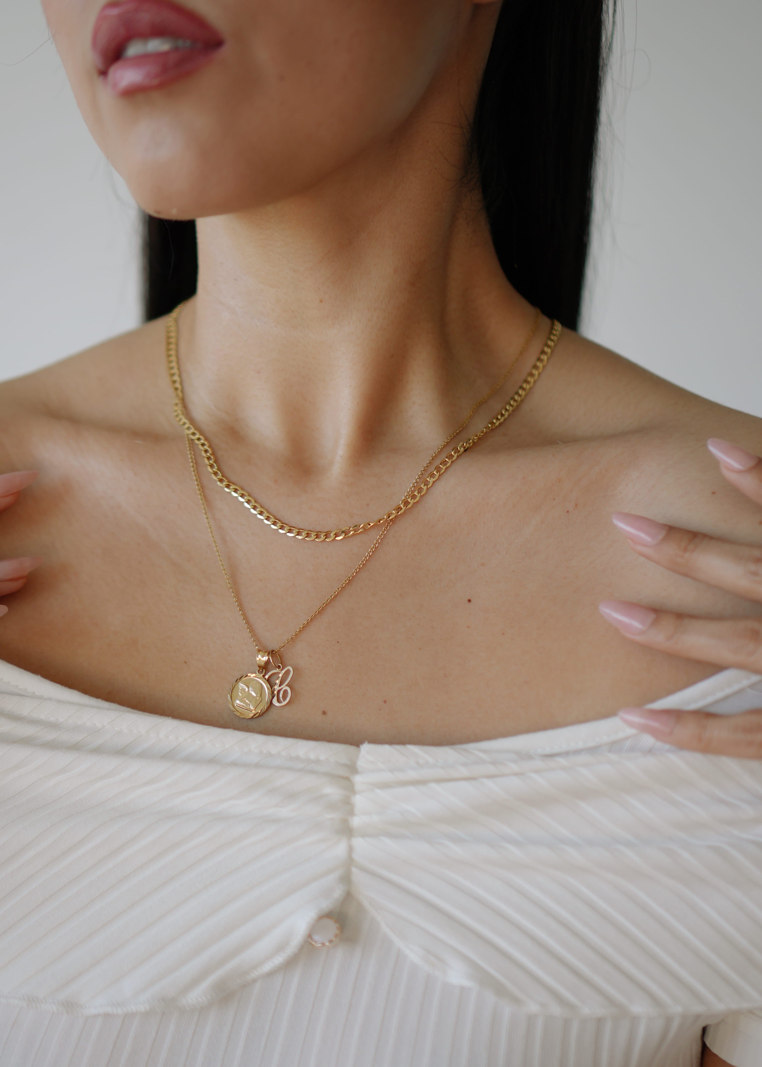Close-up of a person wearing a gold necklace with a pendant.