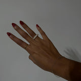 image of a woman's hand against a white backdrop with two gold rings on