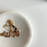 Jewelry including necklaces and earrings on a white dish with a light background