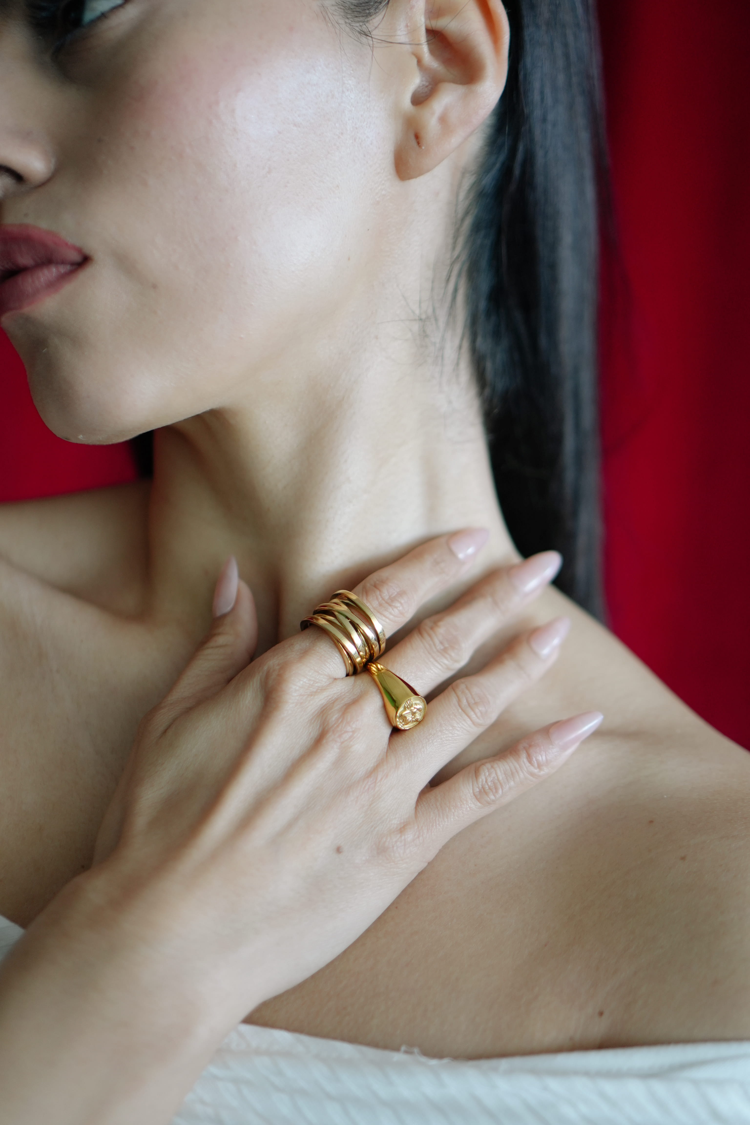 Close-up of a woman's hand with gold rings on a red background