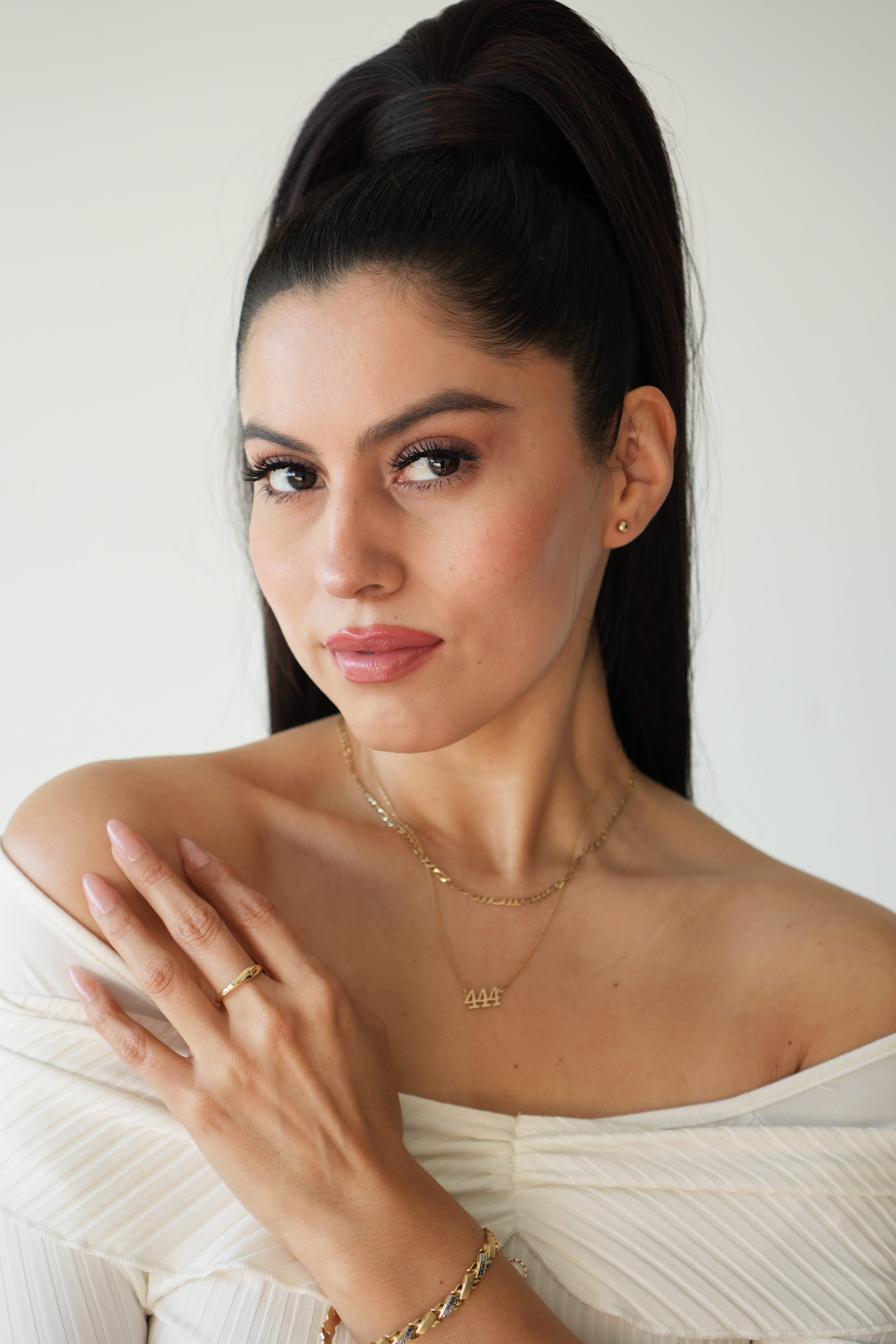 Woman wearing gold jewelry against a white background