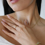 Close-up of a woman's hand wearing a gold ring and bracelet, with a blurred background.