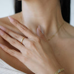 Close-up of a person wearing gold jewelry including a ring, necklace, and bracelet.