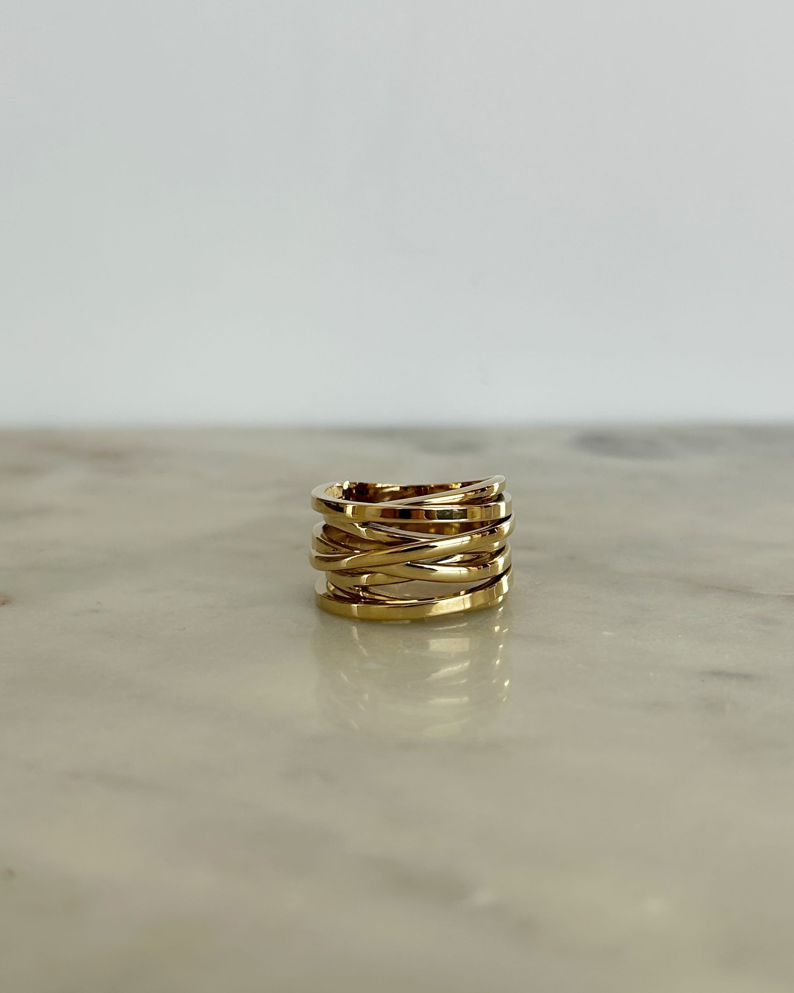 Gold ring on a reflective surface with a light gray background